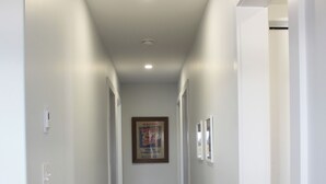 A narrow hallway with a patterned rug, white walls, and a framed picture on the wall. - Water Front Cottage- 10 Min Walk To Barachois Beach, Minutes to North Rustico (North Rustico)