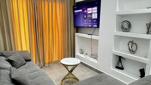 A modern living room with a grey sofa, a small round table, and a mounted TV displaying streaming services. - Refuge of LOVE in Santo Domingo East.  (Santo Domingo Este)