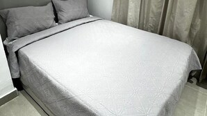 A neatly made bed with a geometric patterned bedspread and two pillows. - Refuge of LOVE in Santo Domingo East.  (Santo Domingo Este)