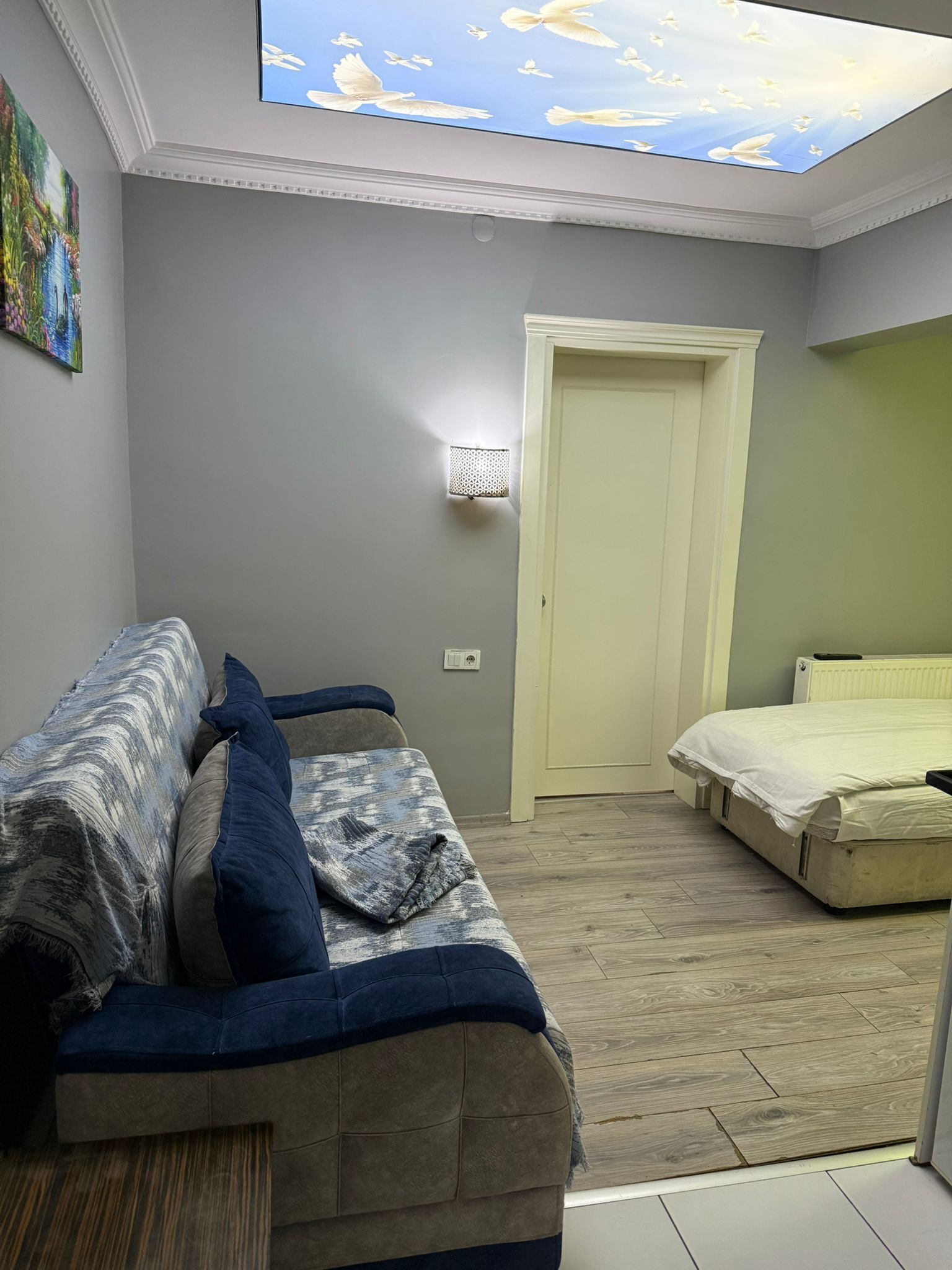 A bedroom with a bed, a sofa, and a skylight.