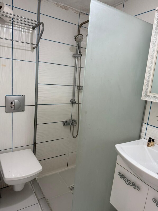 A bathroom with a shower, toilet, and vanity. - HOLİDAY SUİT (İstanbul)