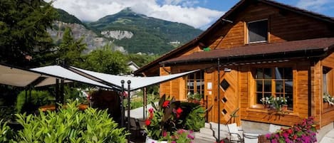 A wooden chalet with a patio, outdoor seating, and a mountain view.