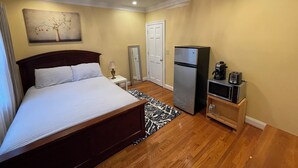 Una habitació d'hotel amb un llit, un refrigerador, una cafetera, un torradora, un mirall i un quadre a la paret.