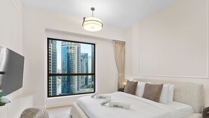 A hotel room with a large bed, a television, a window with a city view, and a ceiling light. - Cozy 3 Bedroom with walking access to JBR Beach (Jumeirah Beach Residence (JBR))