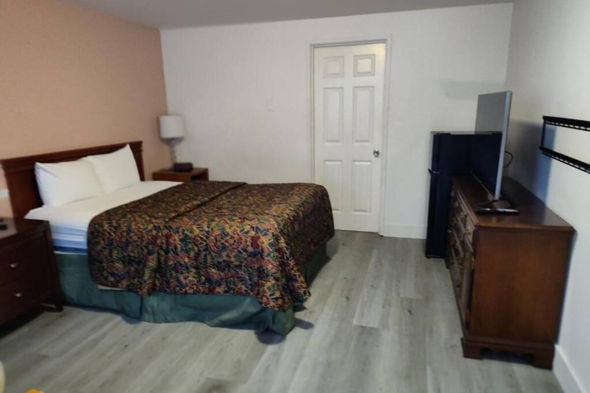 A bedroom with a bed, a dresser, a television, and a door.