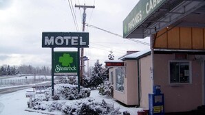 A motel with a green sign, a small building, and a snow-covered landscape. - Shamrock Motel (Bellingham)