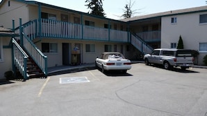A motel with a two-story building, a covered parking area, and a staircase leading to the upper floor. - Shamrock Motel (Bellingham)