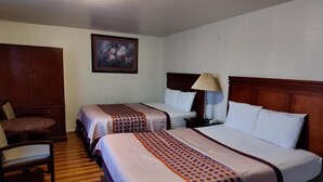 A hotel room with two beds, a wooden wardrobe, a chair, and a bedside table with a lamp. - Shamrock Motel (Bellingham)