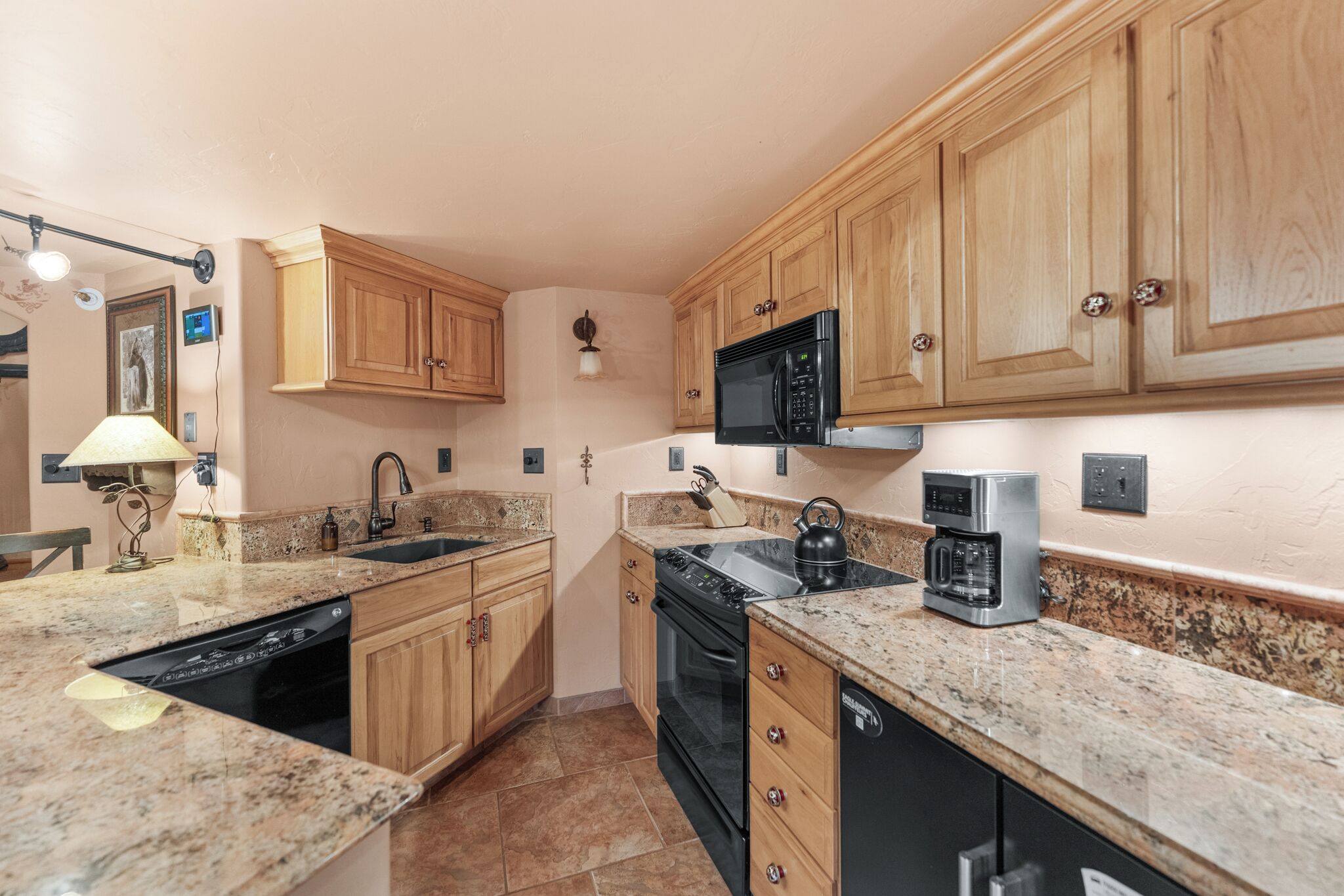 A kitchen with wooden cabinets, a microwave, a coffee maker, and a dishwasher.