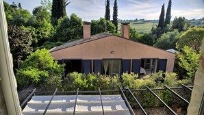 A house with a sloped roof, surrounded by dense greenery, and a visible chimney. - Villa Glicini - Delightful Cottage With Pool (Ostra)