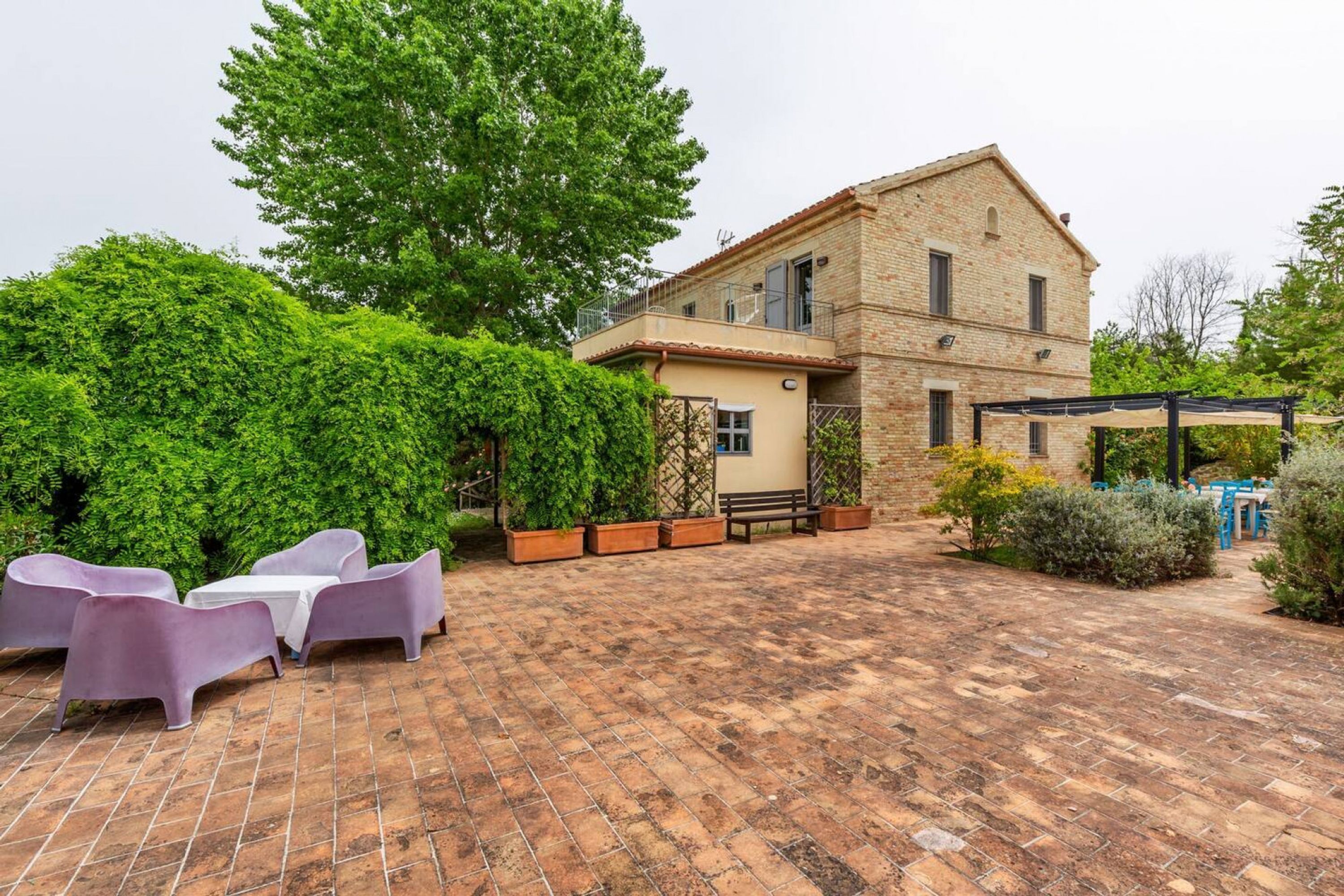 Une maison en briques avec un patio, un espace salon extérieur et de la verdure.