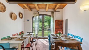 Un comedor con techo de madera, un ventanal con cortinas y vistas a zonas verdes.