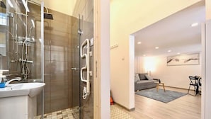 Une salle de bain moderne avec une douche à parois de verre, un lavabo et un sol carrelé.