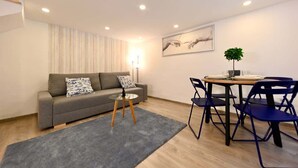 Un salon moderne avec un canapé gris, une petite table ronde et des chaises bleues.