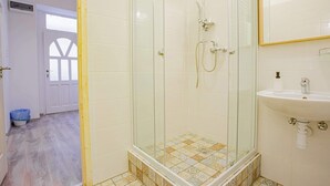A bathroom with a glass shower enclosure, a sink, and a mirror. - Cosy flat in Akácfa str., Aya (Budapest)