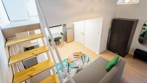A modern interior with a staircase, a sofa, a dining area, and a wardrobe.