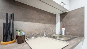 A kitchen with a marble backsplash, a sink, a coffee maker, and a knife block.