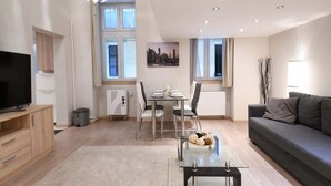 Una sala de estar moderna con un sofá, televisor, mesa de comedor y sillas.