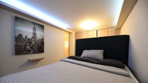 Un dormitorio con una cama, un cartel de paisaje urbano y una lámpara de techo.
