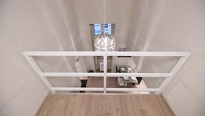 Una habitación con estructura de techo blanca, una lámpara colgante esférica y una zona de comedor con mesa y sillas.