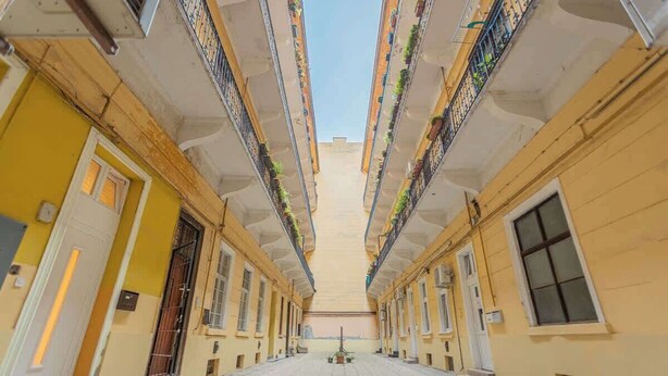 Un patio central con una fuente, rodeado de edificios amarillos con balcones.