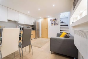 Espaço compacto com cozinha compacta, área de refeições e sofá com vista para a escadaria.