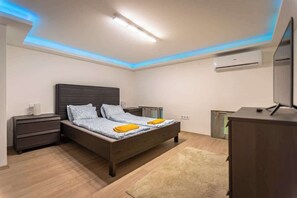 Een slaapkamer met een bed, nachtkastjes, een dressoir en een plafondlamp.