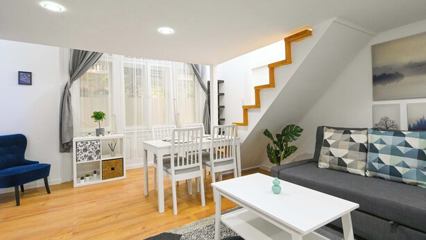A modern living room with a dining area, a staircase, and a sofa.