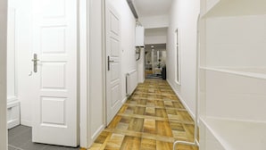 A hallway with white doors, a wooden floor, and a radiator.