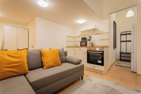 Un espace de vie compact comprenant un canapé, une kitchenette et un petit coin repas.