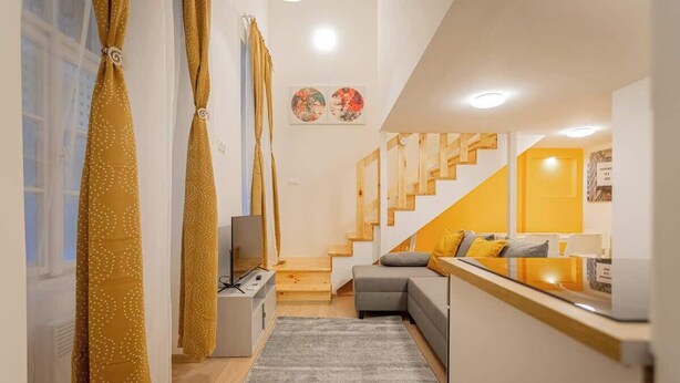 A modern interior with a staircase, a sofa, a TV, and artwork on the walls. - Klauzal  · 2 bedroom downtown flat in Budapest, Lisa (Budapest)
