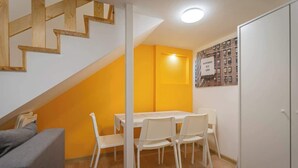 A room with a staircase, a dining table with chairs, a white wardrobe, and a wall with a poster. - Klauzal  · 2 bedroom downtown flat in Budapest, Lisa (Budapest)