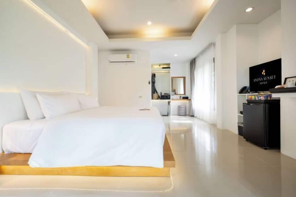 A modern hotel room with a large bed, a desk, and a television.