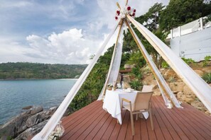 A dining area with a table set for two, overlooking a body of water. - Anona Sunset Boutique (Phuket)