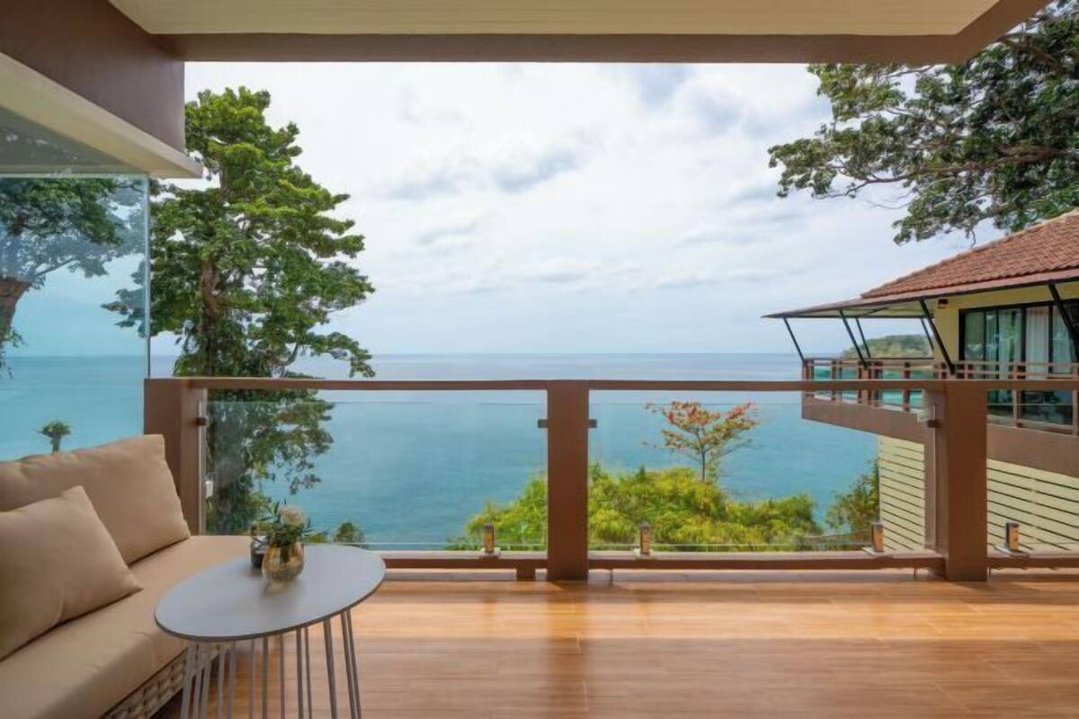 A balcony with a view of the sea, a sofa, and a small table.