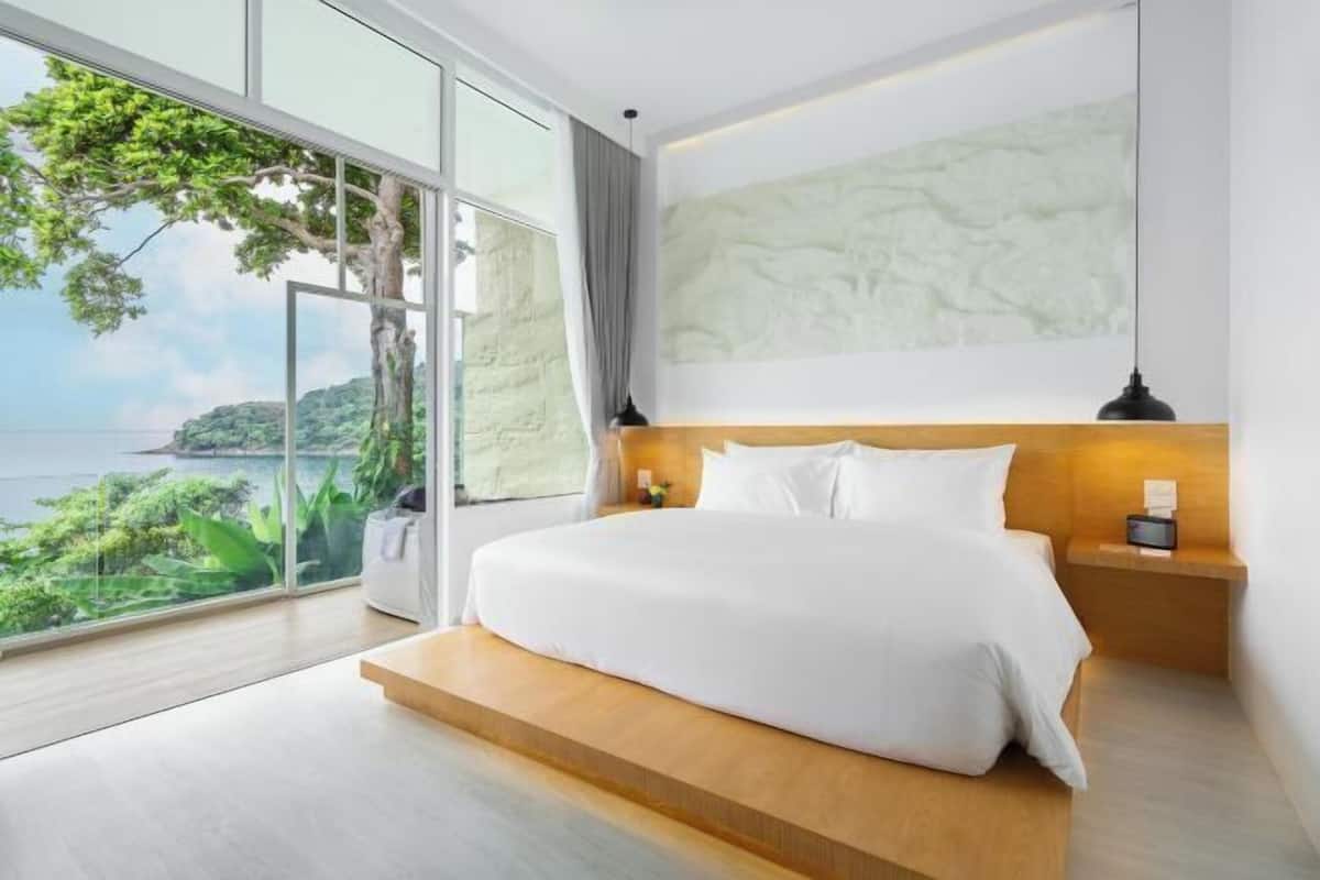A modern bedroom with a large window, a bed, a nightstand, and a wall-mounted lamp.