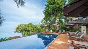 A poolside area with a clear view of the sea, wooden deck, lounge chairs, and umbrellas. - Anona Sunset Boutique (Phuket)