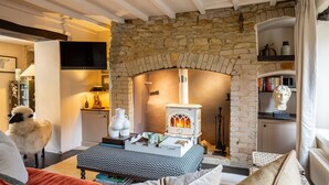 Una sala de estar acogedora con chimenea de piedra, una estantería y una estatua decorativa de oveja.