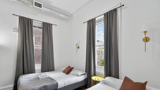A modern hotel room with two beds, grey curtains, a small round yellow table, and a city view. - 1/1 Center City Sleeps 6 Fast Wifi (Philadelphia)