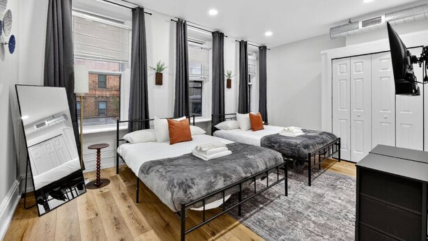 Una habitación de hotel moderna con dos camas, un escritorio y un ventanal grande.