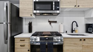 Una cocina moderna con electrodomésticos de acero inoxidable, armarios de madera, un microondas, una estufa a gas y un fregadero.