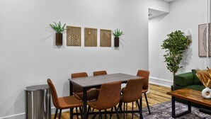 Un comedor moderno con una mesa rectangular y seis sillas, un cubo de basura y paneles decorativos en la pared.