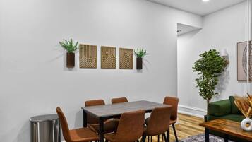 Un espace repas moderne avec une table rectangulaire et six chaises, une poubelle et des panneaux muraux décoratifs.