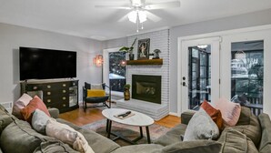 A living room with a fireplace, a television, and a sofa. - Forest Lake Retreat | Backyard Sanctuary & Hot Tub (Columbia)