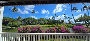 A tropical garden with palm trees, a pond, and vibrant pink flowers.