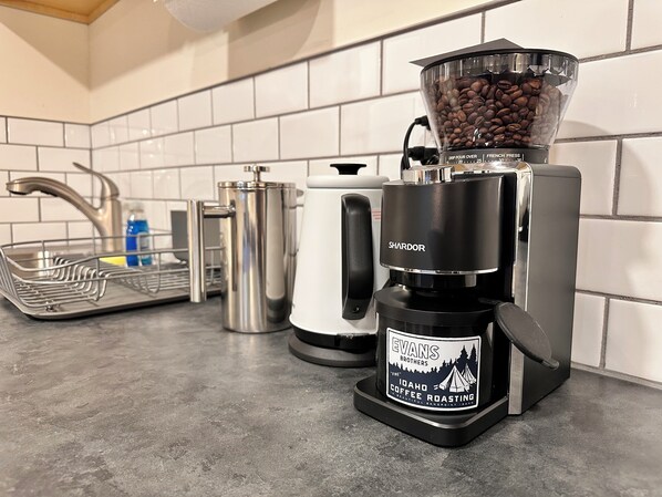 A coffee maker on a kitchen counter with a coffee grinder and a kettle. - Basecamp (Sagle)