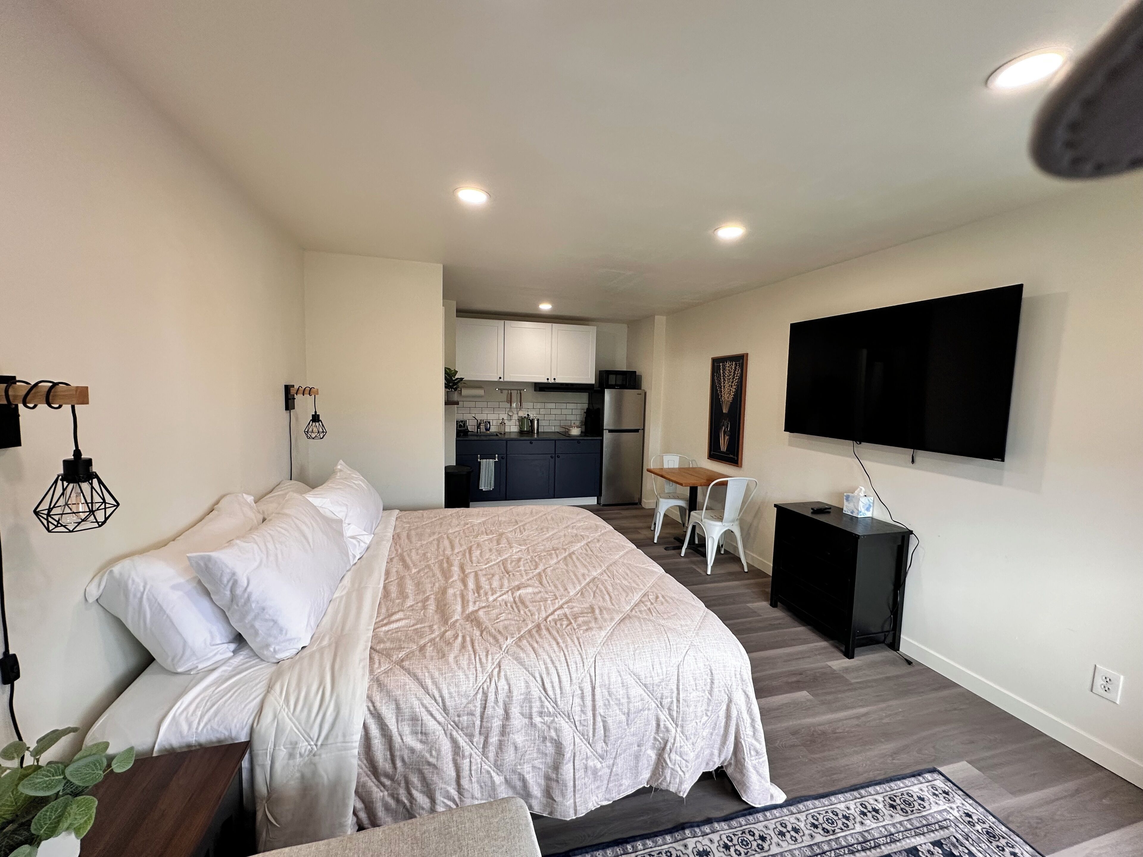 A modern bedroom with a large bed, a desk, and a TV.