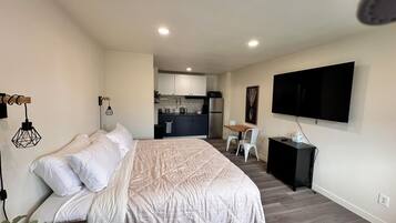 A modern bedroom with a large bed, a desk, and a TV.