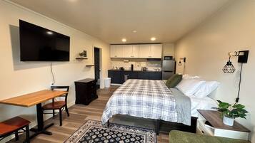 Un dormitorio moderno y compacto con cama, mesita de noche y pequeño espacio de escritorio.