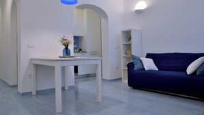 A modern living room with a white table, a blue sofa, and a blue pendant light. - In an old fishing village apartment with sea view terrace (Ischia)